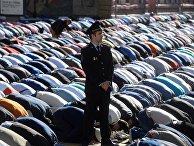 Сотрудник правоохранительных органов перед намазом в день праздника Ураза-байрам у Соборной мечети в Москве