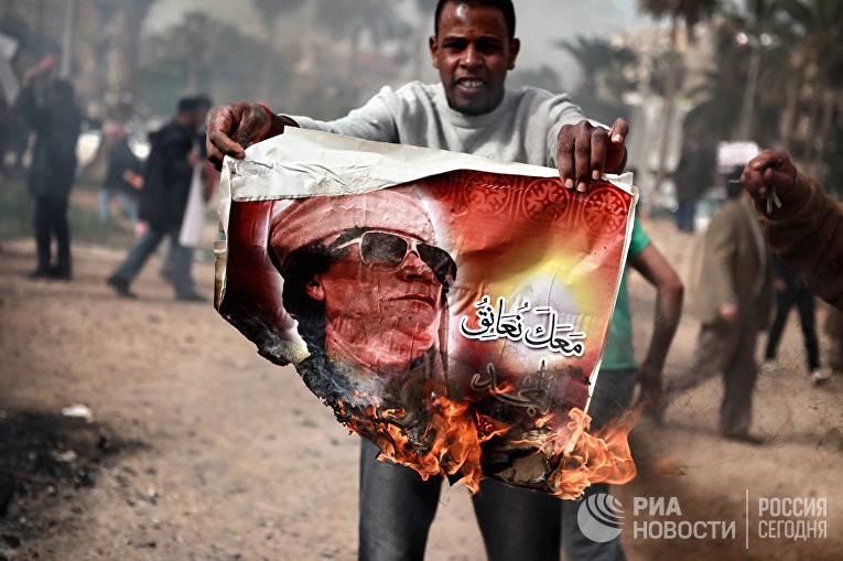 Житель Бенгази сжигает портрет Муамара Каддафи