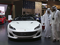 Посетители перед автомобилем Ferrari Portofino на Dubai Motor Show в ОАЭ. 14 ноября 2017