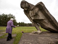 Женщина возлагает цветы к мемориалу памяти жертв фашизма на месте концлагеря "Саласпилс" в Латвии