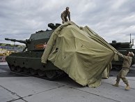 Сотрудники снимают тент с 152-миллиметровой самоходной артиллерийской установки «Коалиция-СВ» Сотрудники снимают тент с 152-миллиметровой самоходной артиллерийской установки «Коалиция-СВ»