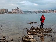 Молодой человек стоит на берегу Дуная в Будапеште Молодой человек стоит на берегу Дуная в Будапеште