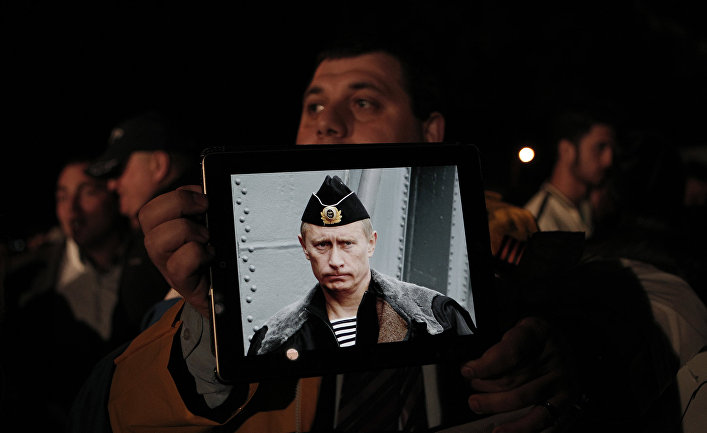 Протестующие с фотографией президента России Владимира Путина во время акции протеста у здания кипрского парламента