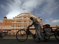 Велорикша проезжает мимо Дворца ветров в Джайпуре, Индия Велорикша проезжает мимо Дворца ветров в Джайпуре, Индия