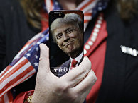 Женщина держит телефон с фотографией Дональда Трампа во время предвыборной кампании в США Женщина держит телефон с фотографией Дональда Трампа во время предвыборной кампании в США