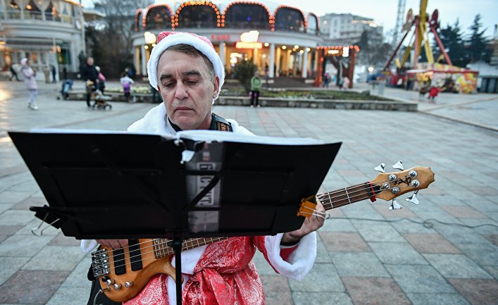 Музыкант в костюме Деда Мороза выступает на набережной в Ялте, Крым