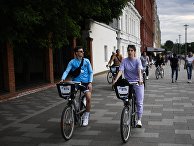 Люди катаются на велосипедах по Берсеневской набережной в Москве Люди катаются на велосипедах по Берсеневской набережной в Москве