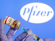 30 октября 2020. Медработник набирает препарат на фоне логотипа Pfizer 30 октября 2020. Медработник набирает препарат на фоне логотипа Pfizer