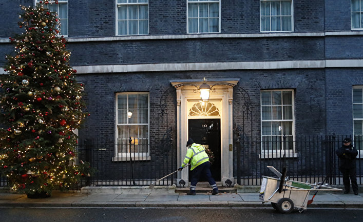 Уборщик подметает перед дверью резиденции премьер-министра Великобритании на Даунинг-стрит, 10, Лондон
