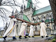 Священнослужители несут крест в католический собор в Тронхейме, Норвегия, в Страстную пятницу Священнослужители несут крест в католический собор в Тронхейме, Норвегия, в Страстную пятницу
